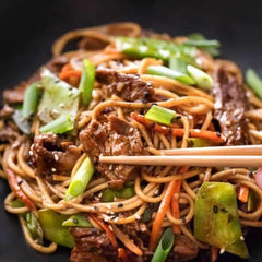 sesame beef stir fry with chopsticks and green vegetables